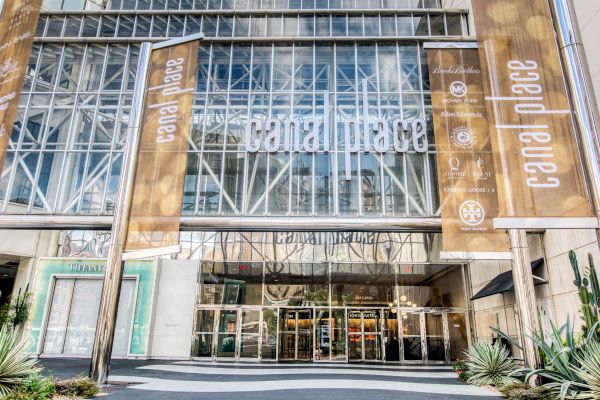 The image shows the entrance of a shopping center named Canal Place, with large glass windows and decorative banners.